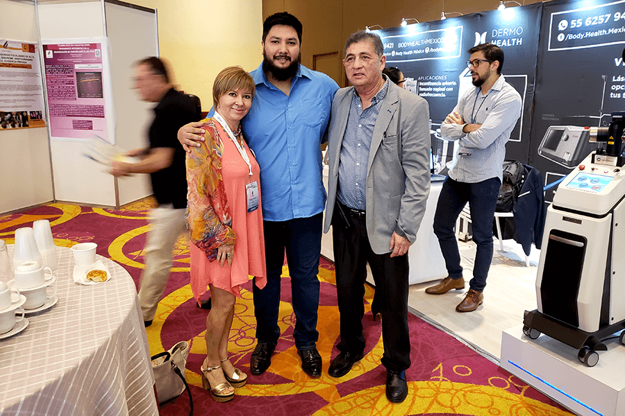 Asistentes junto a stands de equipos médicos y pósters científicos en el área de exposición